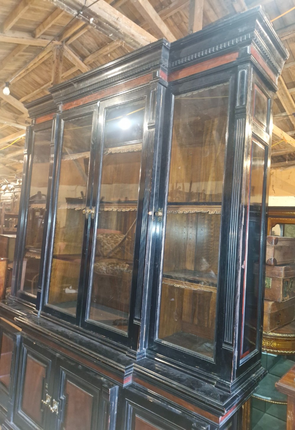 A large Victorian ebonised and mahogany breakfront library bookcase featuring glazed upper doors, panelled lower cupboards, and fluted side pilasters. View X