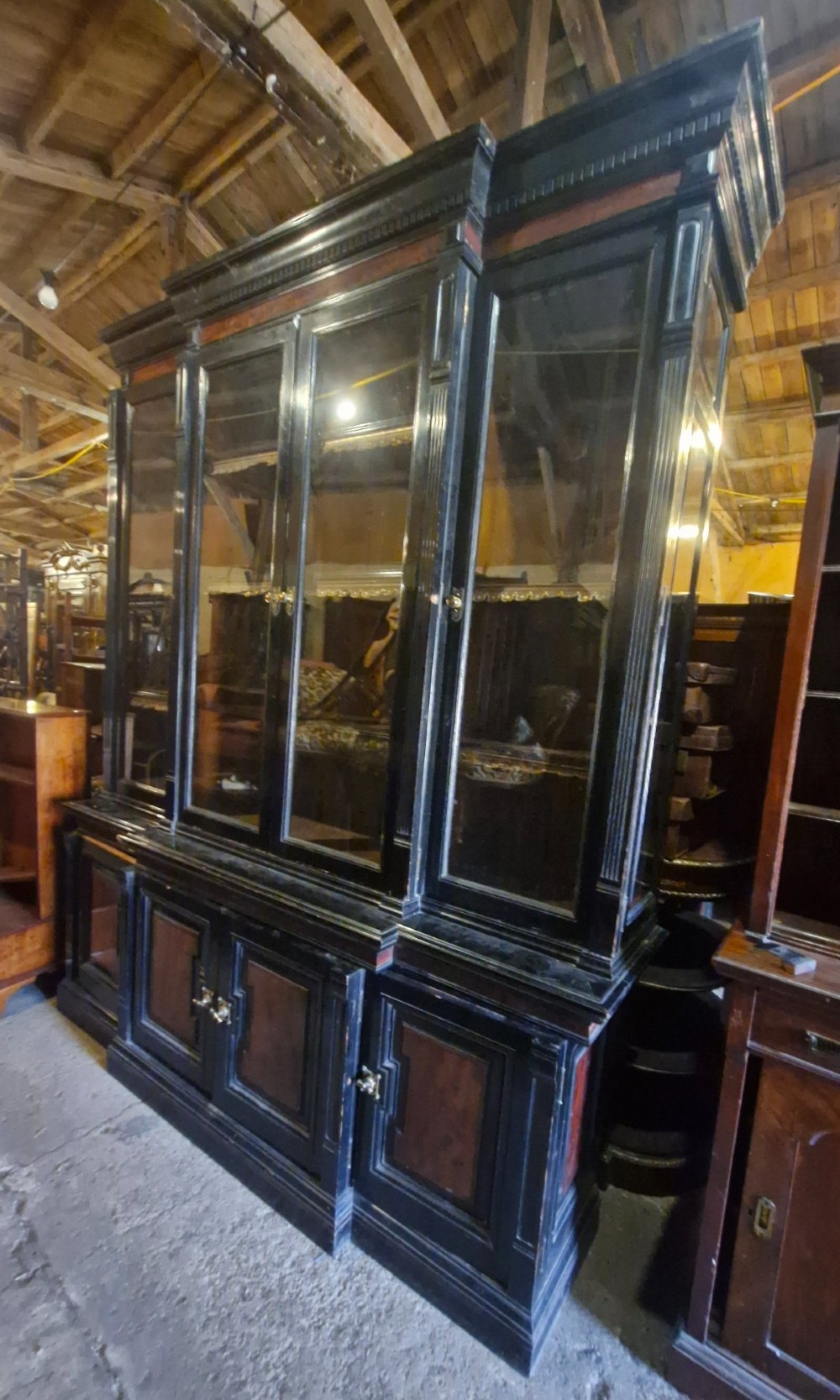 A large Victorian ebonised and mahogany breakfront library bookcase featuring glazed upper doors, panelled lower cupboards, and fluted side pilasters. View XI