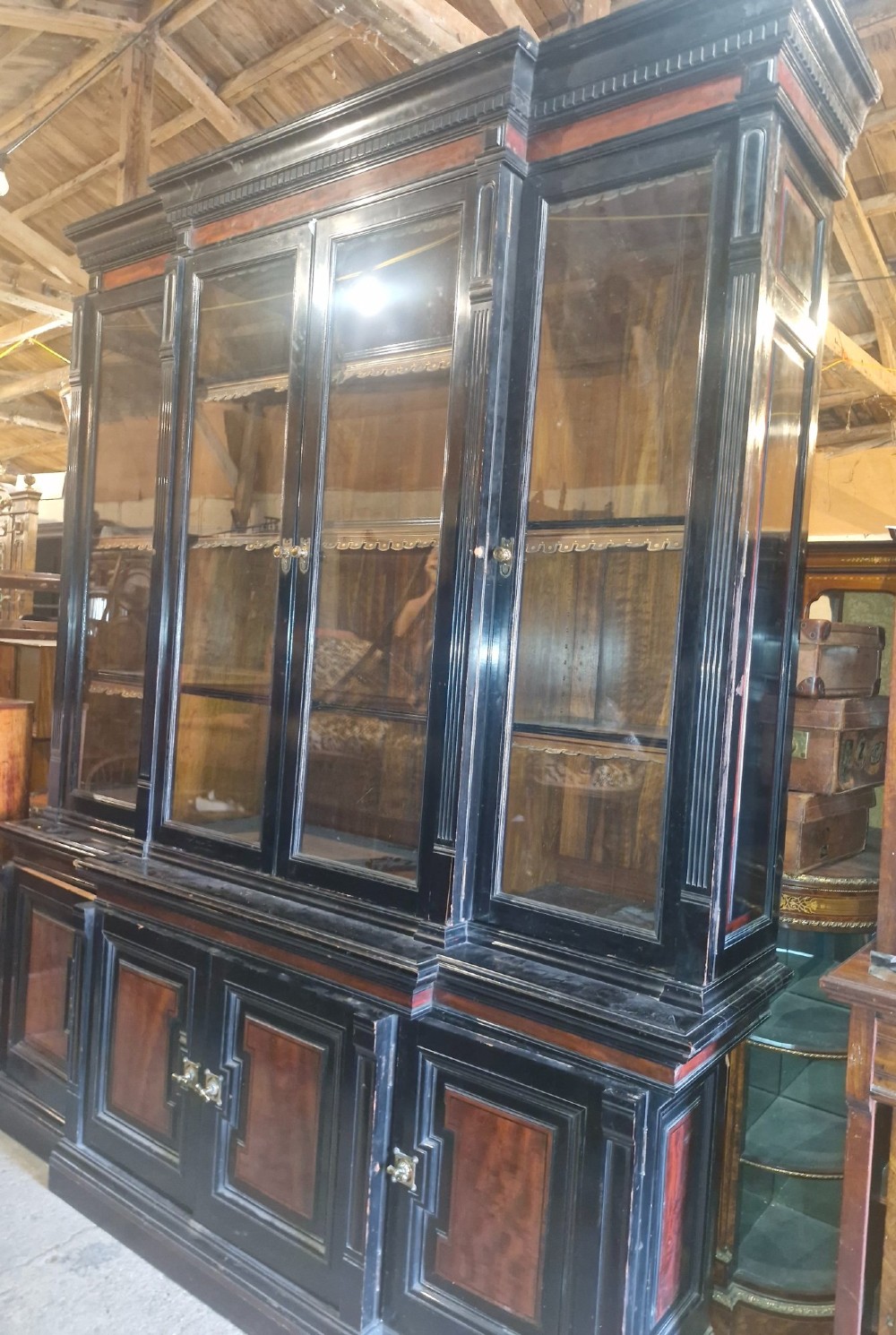 A large Victorian ebonised and mahogany breakfront library bookcase featuring glazed upper doors, panelled lower cupboards, and fluted side pilasters. View XII