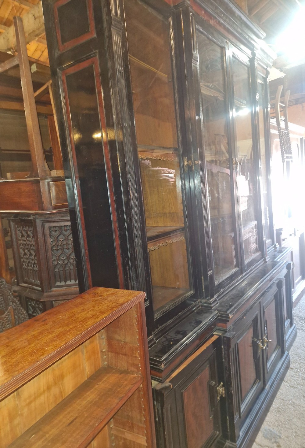 A large Victorian ebonised and mahogany breakfront library bookcase featuring glazed upper doors, panelled lower cupboards, and fluted side pilasters. View XIV