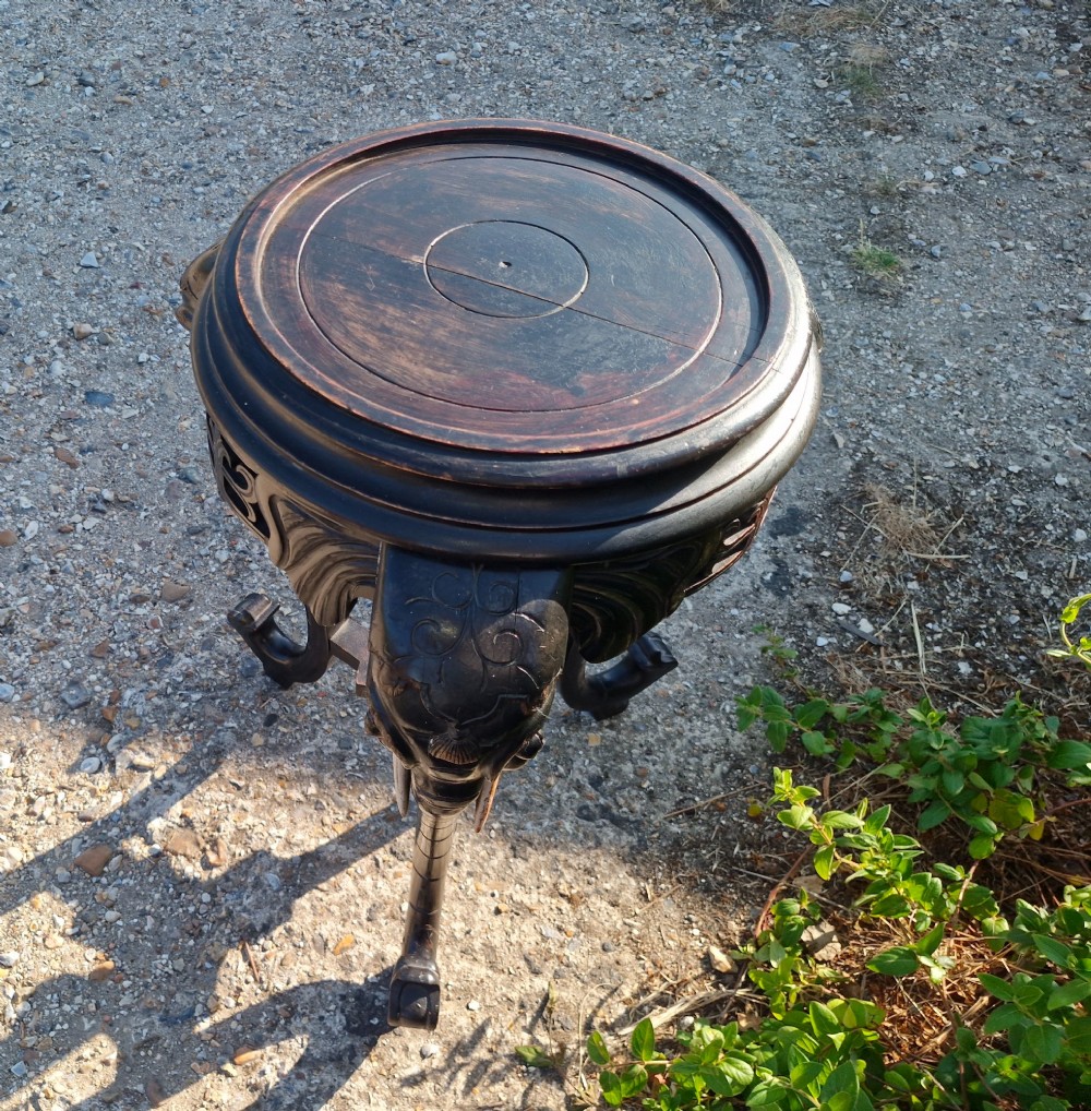 A late Victorian ebonised wood tripod side table featuring three carved elephant heads whose trunks extend to form table legs, set with light-coloured wooden tusks. View V