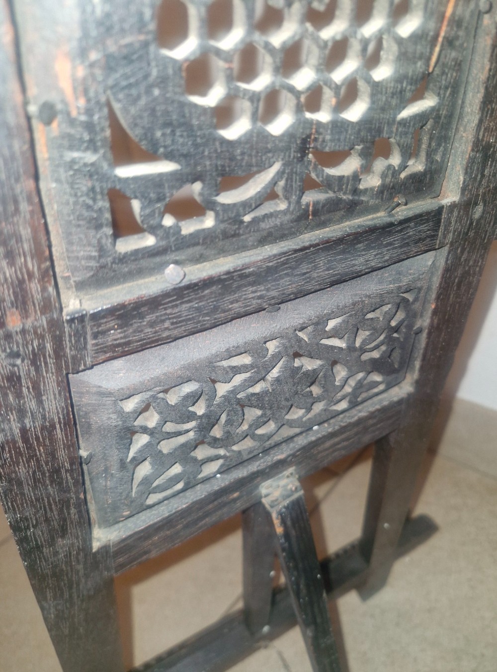 An intricate dark carved wooden tabletop display easel featuring pierced fretwork and floral motifs. View II