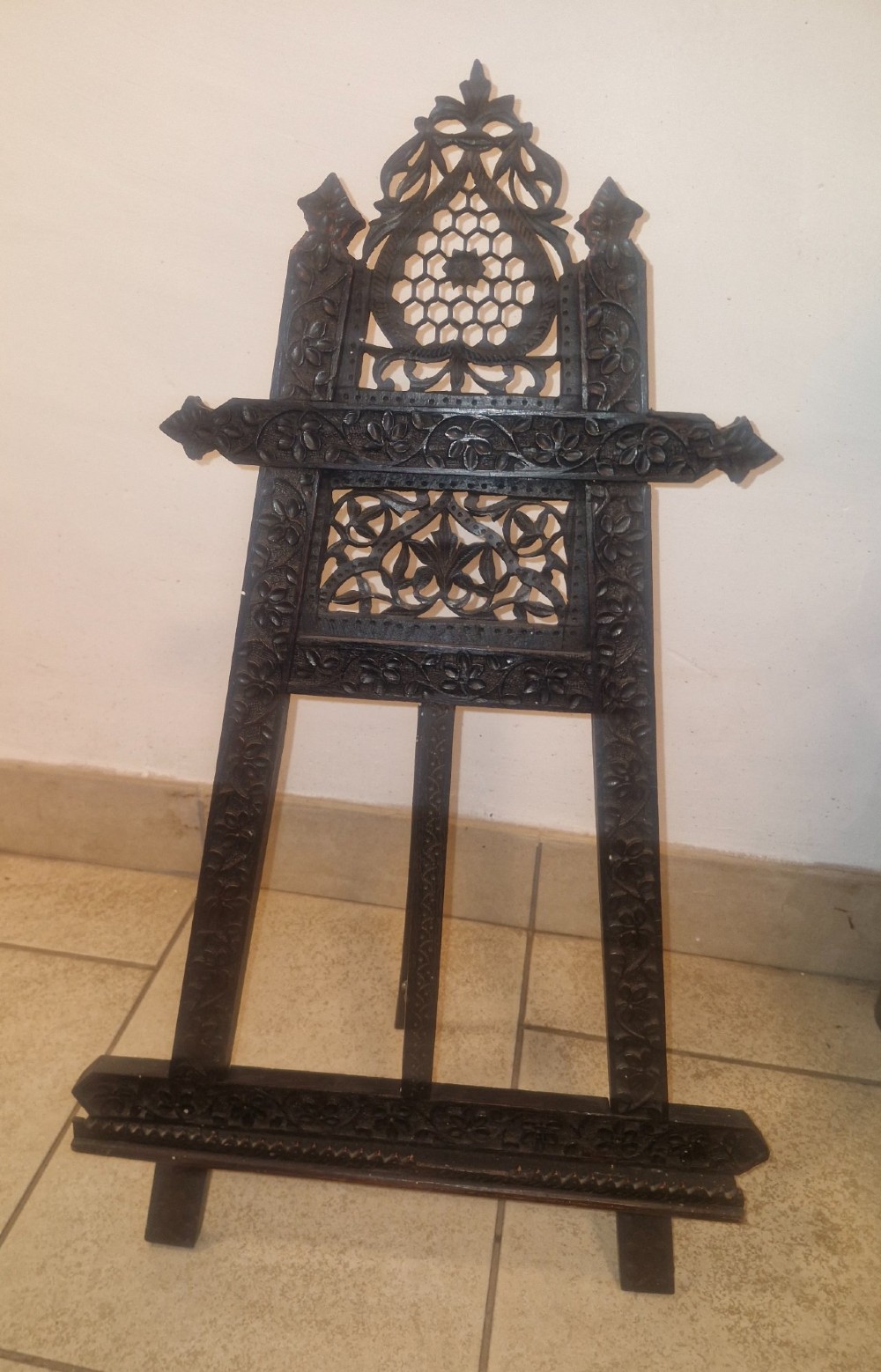 An intricate dark carved wooden tabletop display easel featuring pierced fretwork and floral motifs. View III