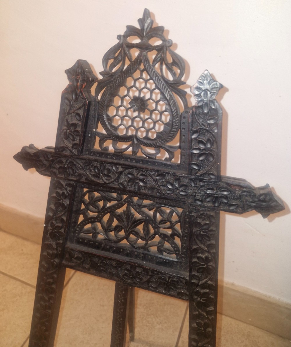 An intricate dark carved wooden tabletop display easel featuring pierced fretwork and floral motifs. View IV