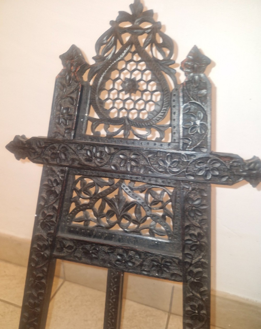 An intricate dark carved wooden tabletop display easel featuring pierced fretwork and floral motifs. View VI