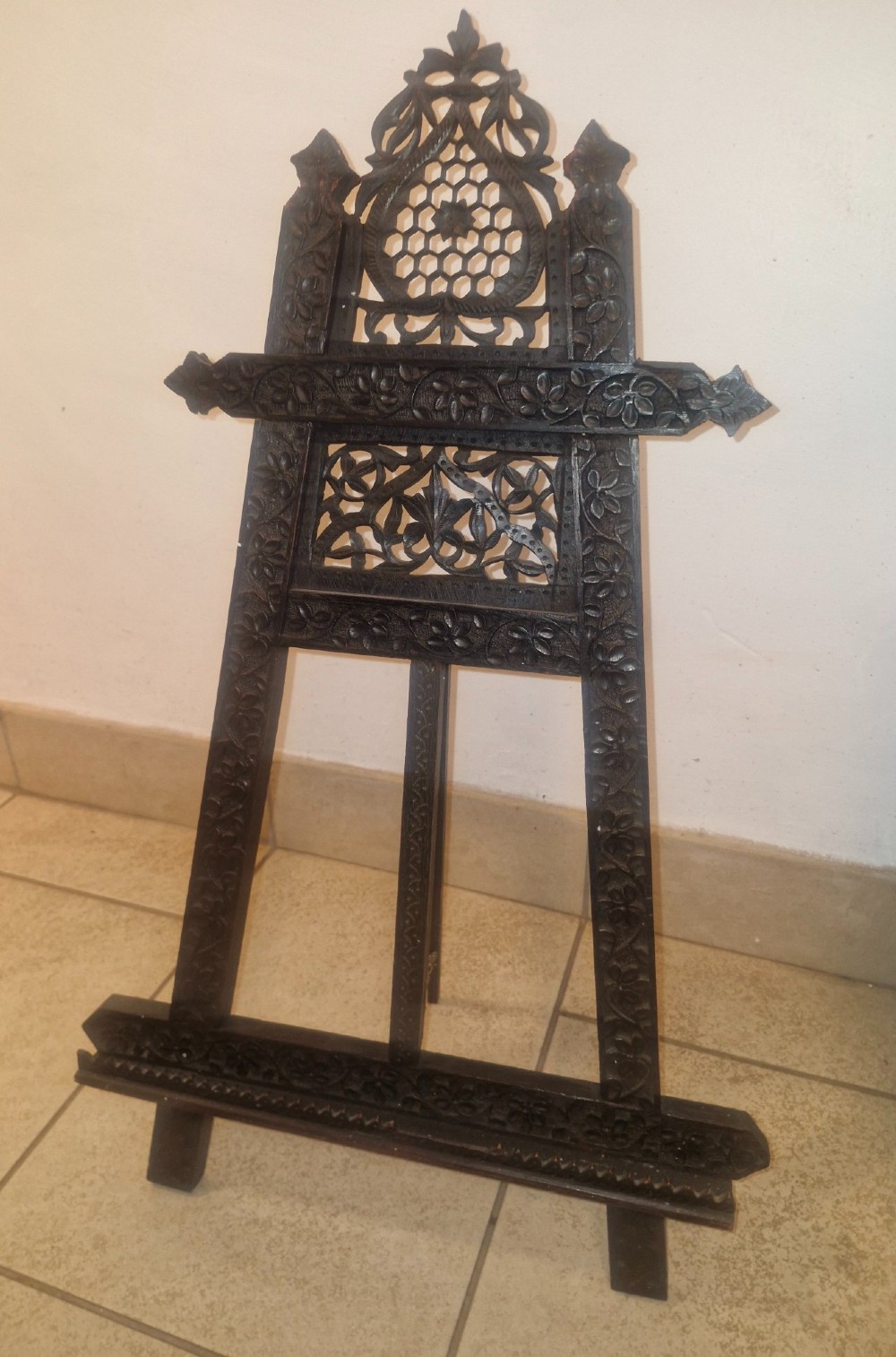 An intricate dark carved wooden tabletop display easel featuring pierced fretwork and floral motifs. View VII