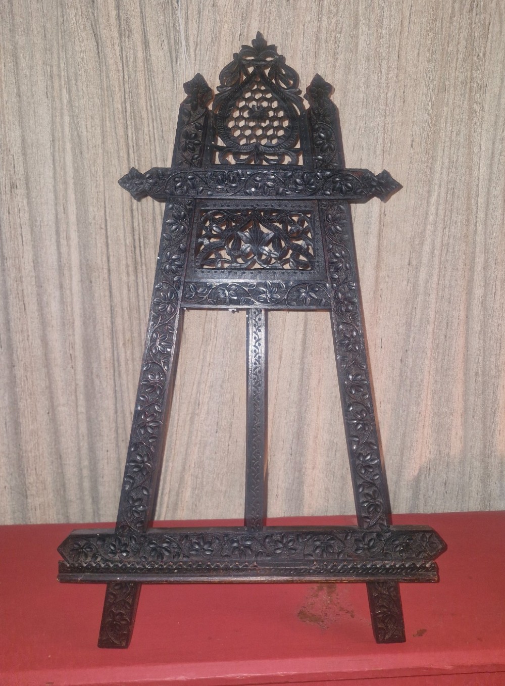 An intricate dark carved wooden tabletop display easel featuring pierced fretwork and floral motifs. View IX