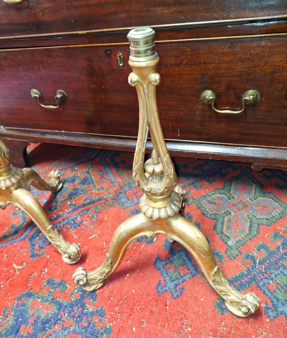 A pair of carved wood tripod bases featuring aged gold leaf gilding, scrolled tripod legs, and acanthus leaf carving. View VI