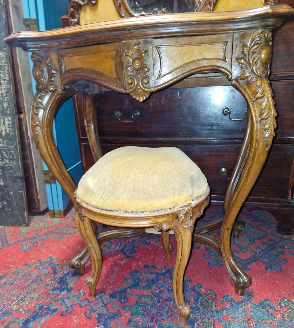 A French Rococo Revival carved walnut dressing table featuring an integrated oval mirror and a matching upholstered stool. View V