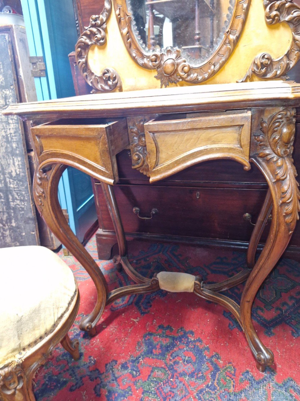 A French Rococo Revival carved walnut dressing table featuring an integrated oval mirror and a matching upholstered stool. View VI
