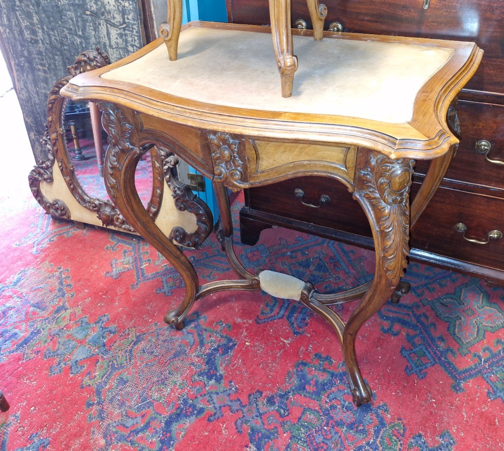 A French Rococo Revival carved walnut dressing table featuring an integrated oval mirror and a matching upholstered stool. View X