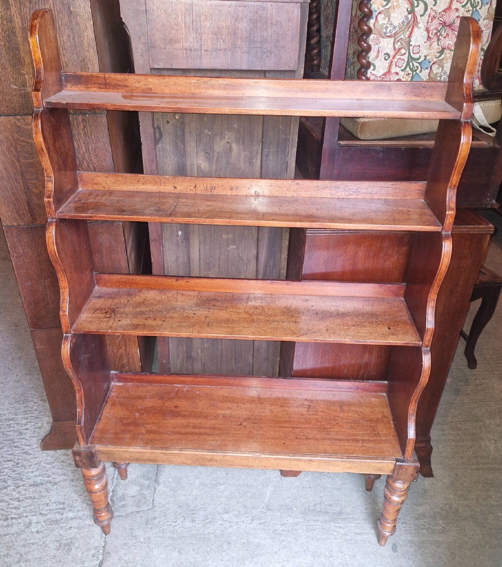 A 19th-century mahogany waterfall bookcase featuring four open graduated shelves, curved side profiles, and turned front legs.