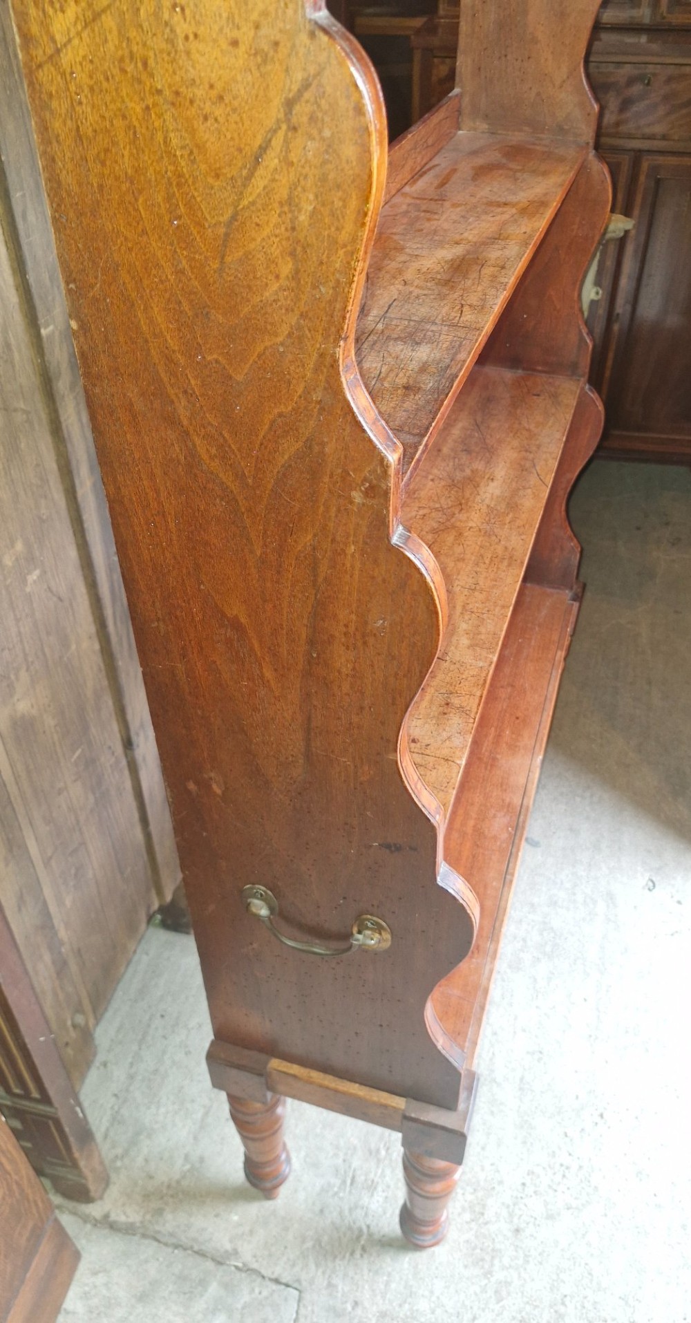 A 19th-century mahogany waterfall bookcase featuring four open graduated shelves, curved side profiles, and turned front legs. View II