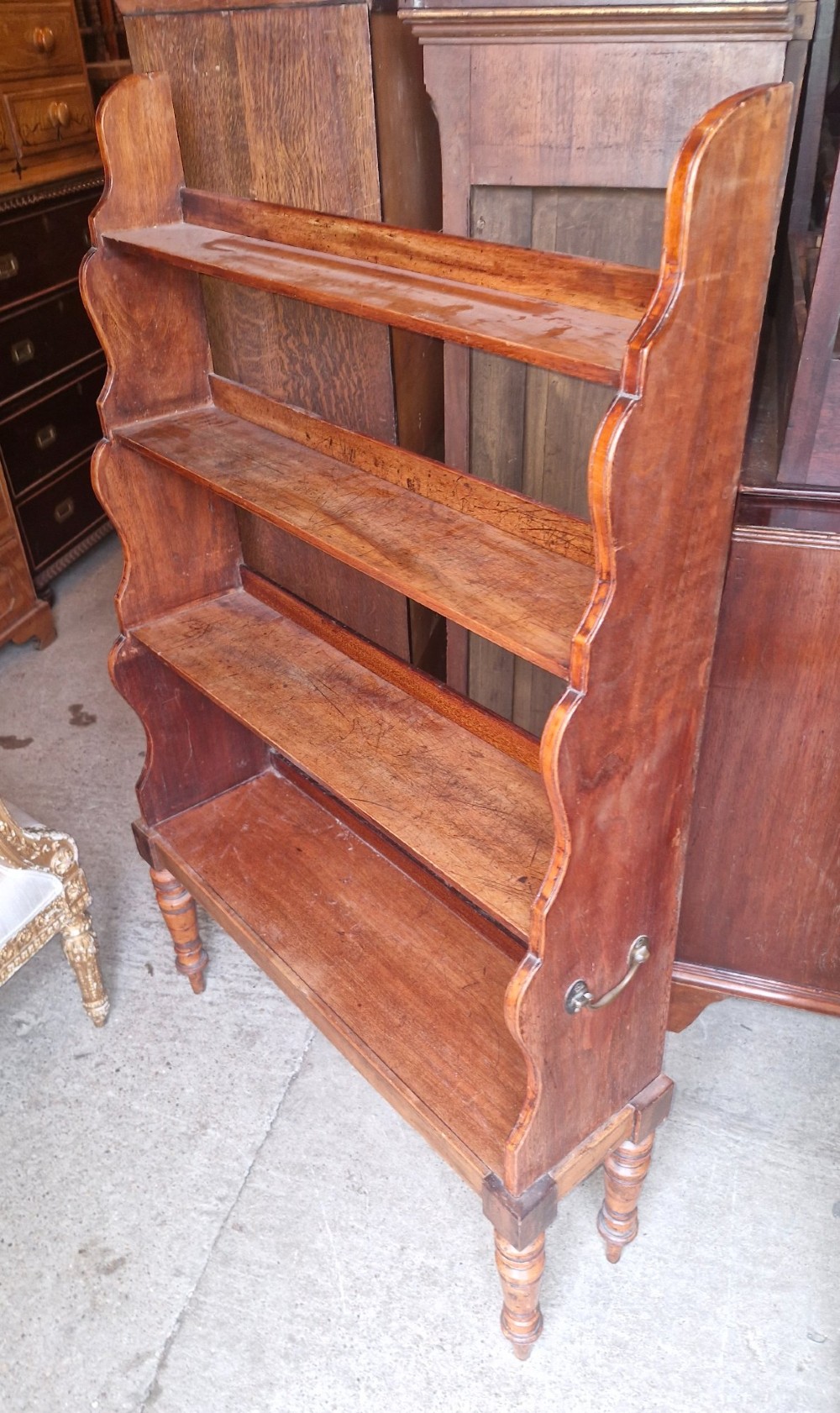 A 19th-century mahogany waterfall bookcase featuring four open graduated shelves, curved side profiles, and turned front legs. View III