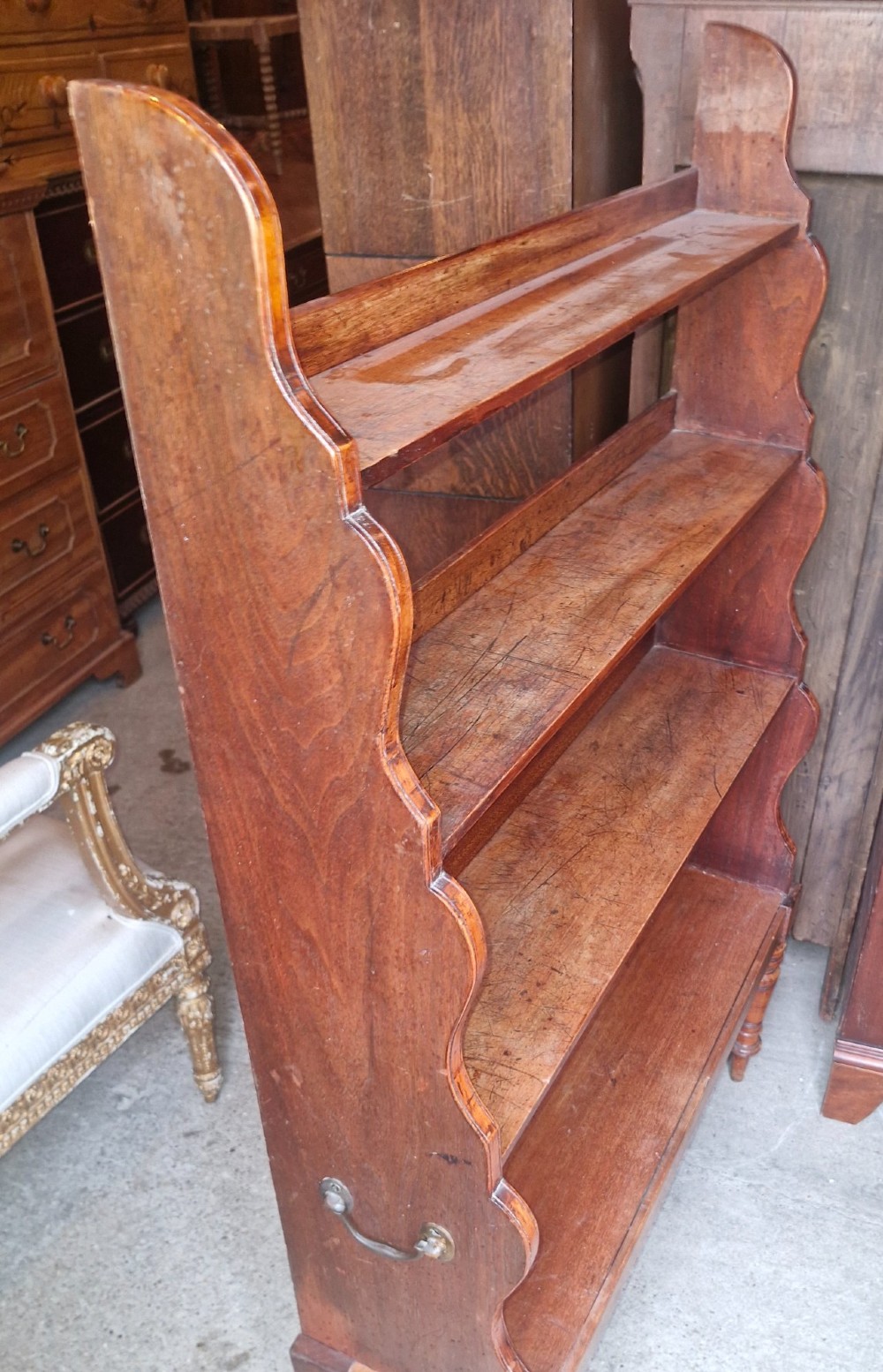 A 19th-century mahogany waterfall bookcase featuring four open graduated shelves, curved side profiles, and turned front legs. View V