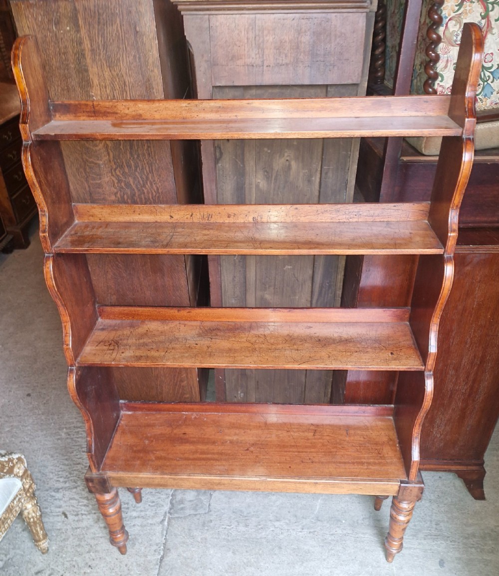 A 19th-century mahogany waterfall bookcase featuring four open graduated shelves, curved side profiles, and turned front legs. View VI