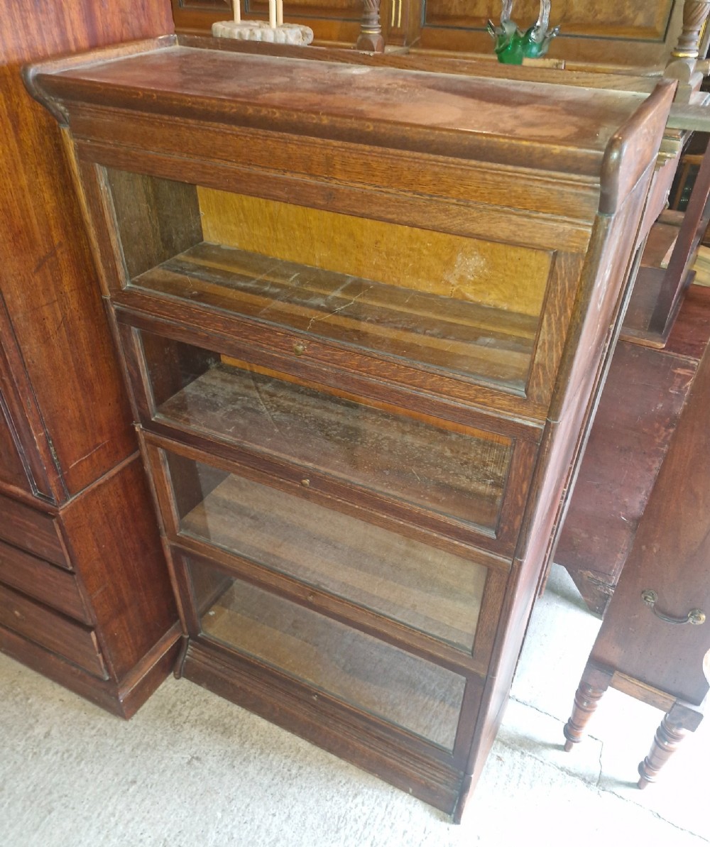 A four-tier oak sectional bookcase featuring glazed up-and-over doors and small brass knob handles. View II