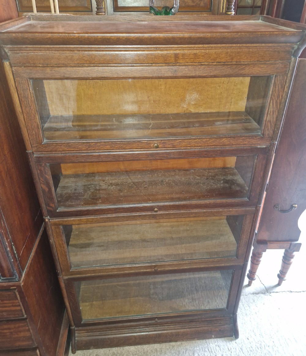A four-tier oak sectional bookcase featuring glazed up-and-over doors and small brass knob handles. View V
