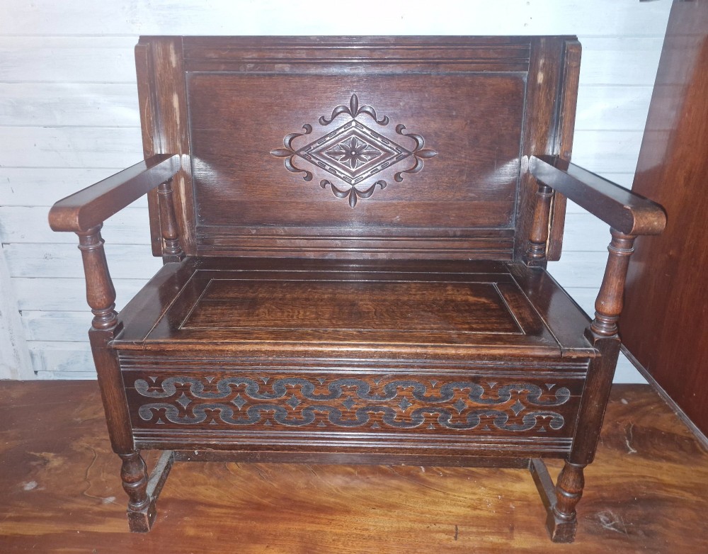 A dark oak monks bench featuring a carved diamond-patterned backrest, turned arm supports, carved front panel, and a lift-up seat. View VIII
