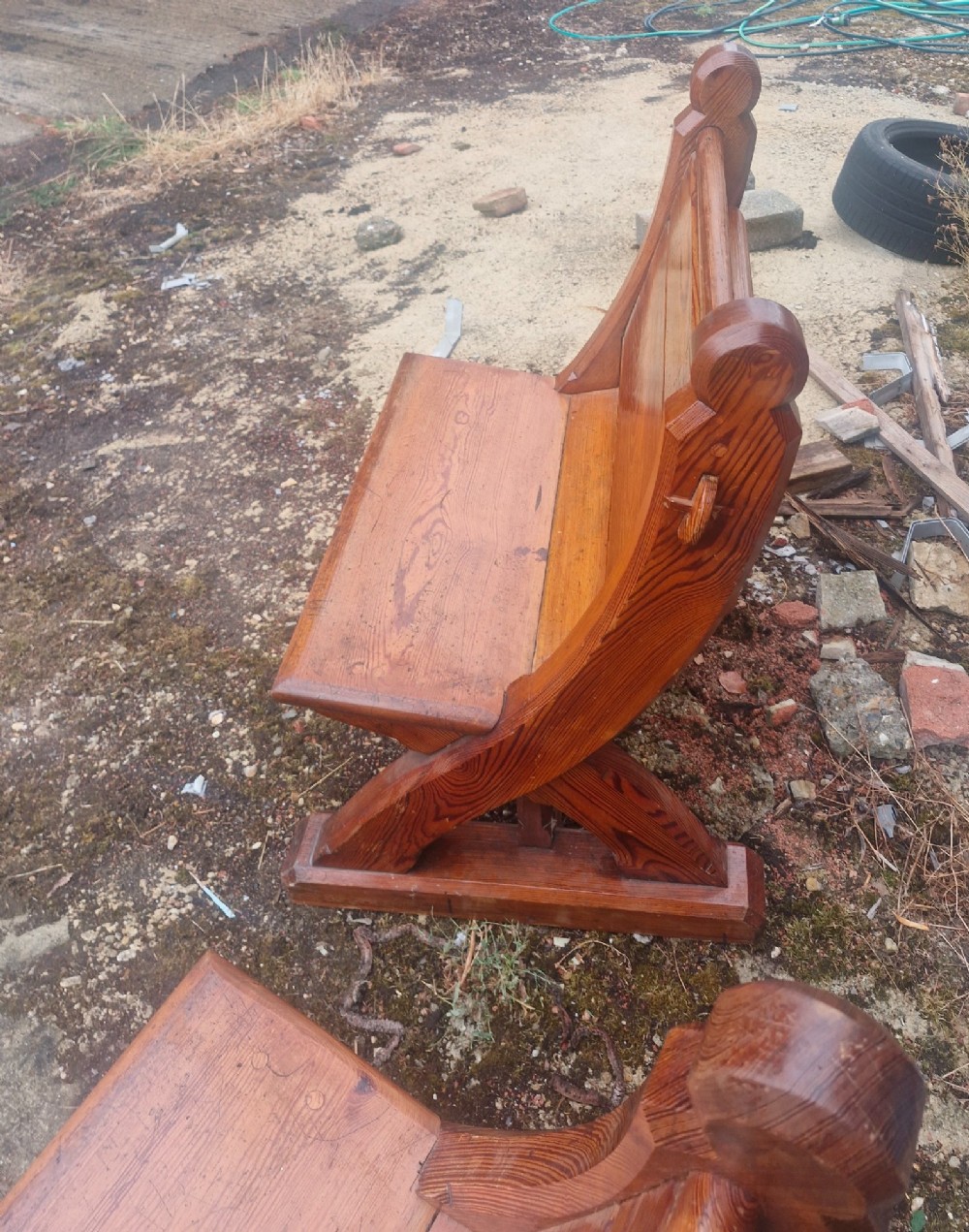 A pair of warm brown pitch pine hall seats with slatted backrests and carved Gothic side supports on plinth bases. View II