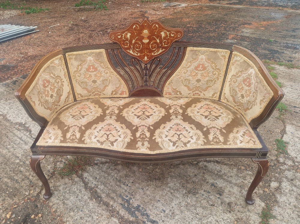 An Edwardian mahogany settee featuring central floral marquetry inlay, patterned damask upholstery, and cabriole legs. View V