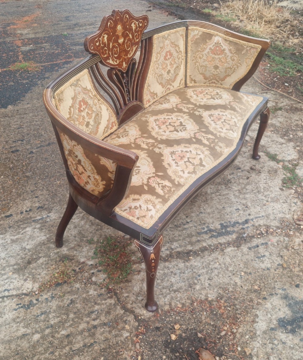 An Edwardian mahogany settee featuring central floral marquetry inlay, patterned damask upholstery, and cabriole legs. View VI