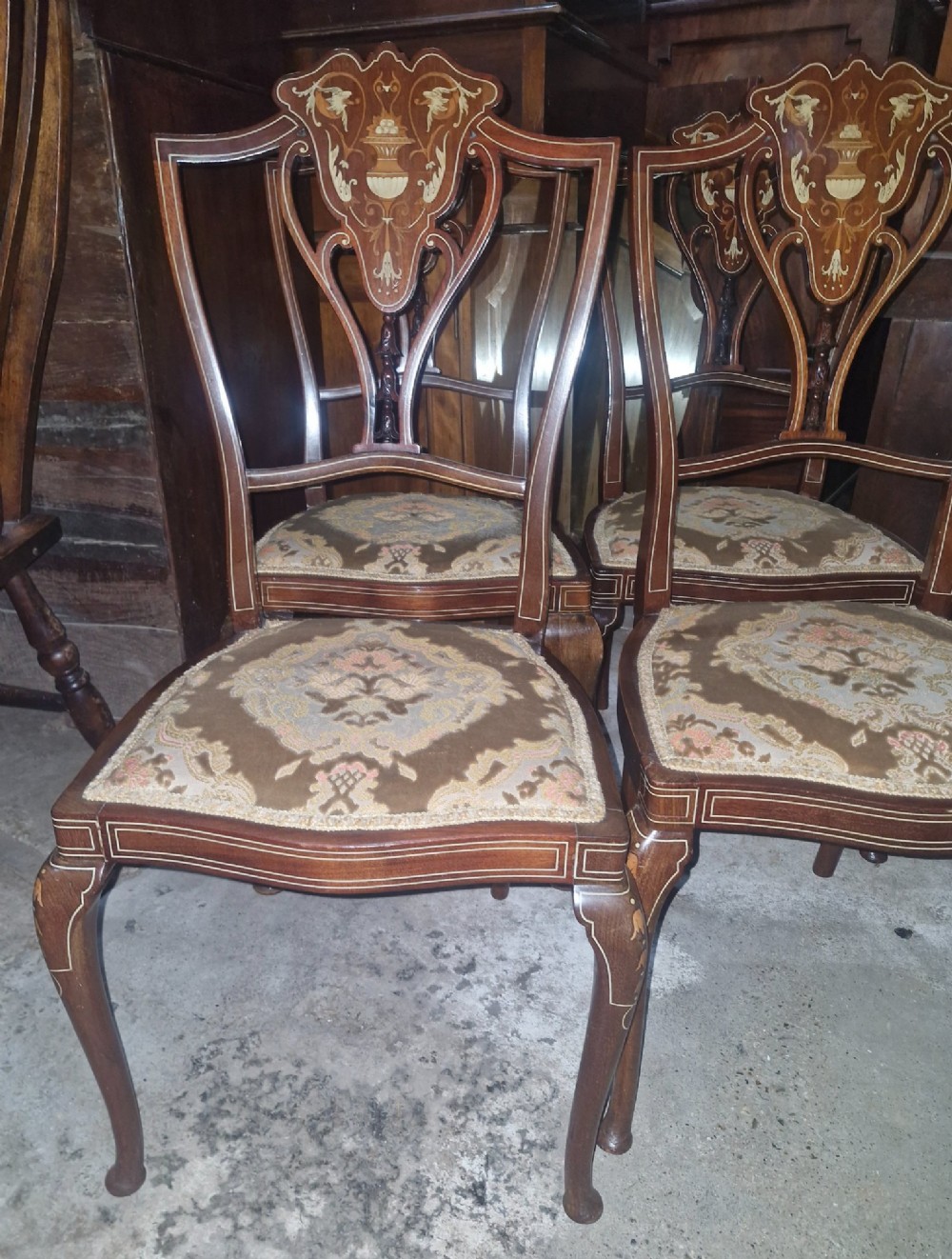 A set of four Edwardian mahogany side chairs featuring inlaid vasiform splats, cabriole front legs, and pattern-upholstered seats.
