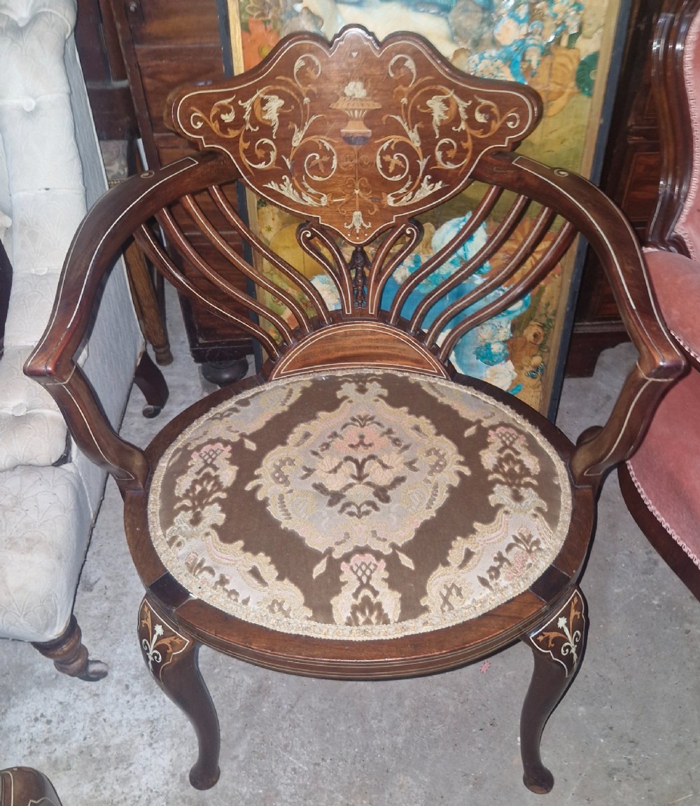 An Edwardian mahogany tub chair featuring floral marquetry inlay on the back splat, sweeping armrests, and an upholstered seat.