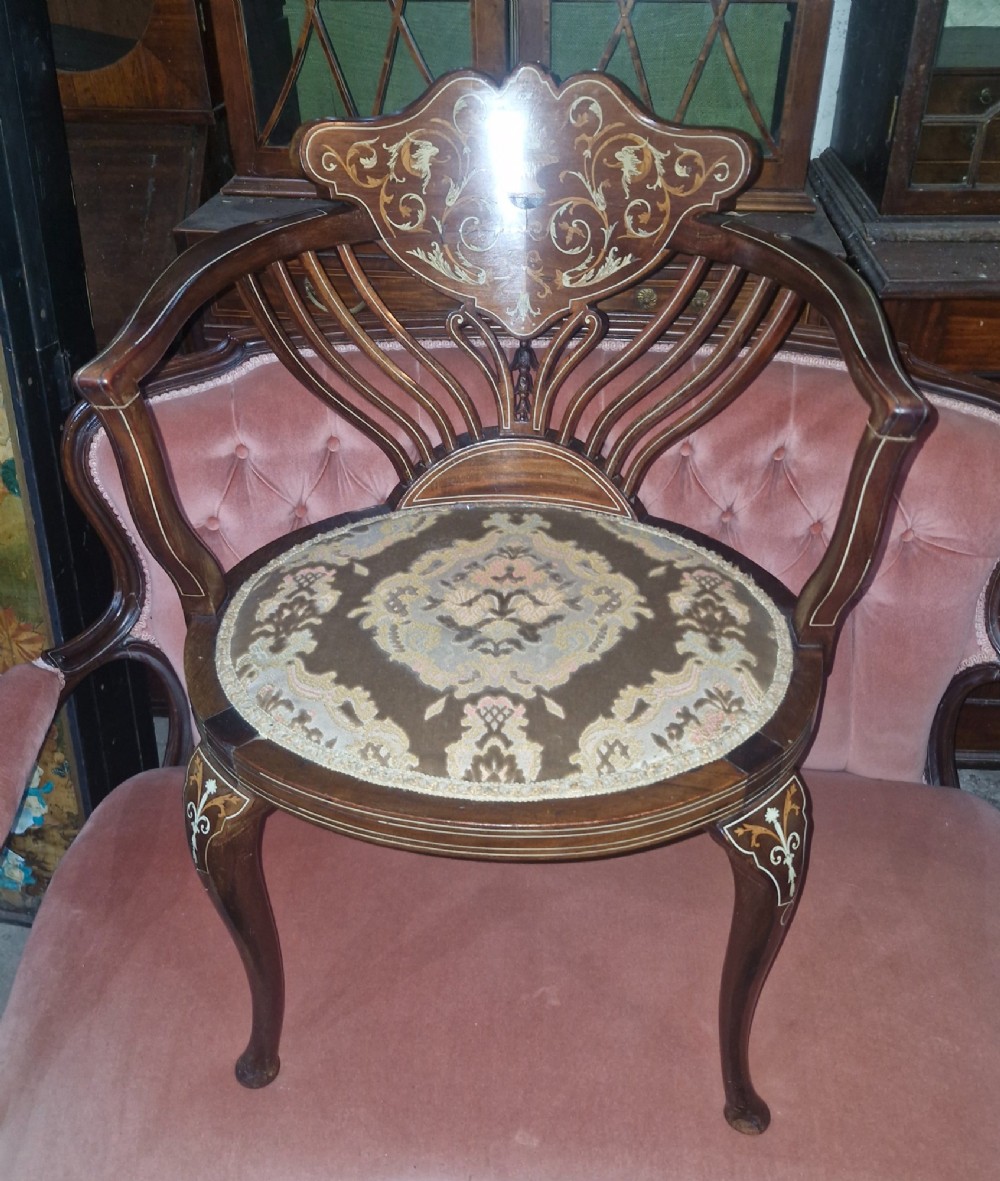 An Edwardian mahogany tub chair featuring floral marquetry inlay on the back splat, sweeping armrests, and an upholstered seat. View V