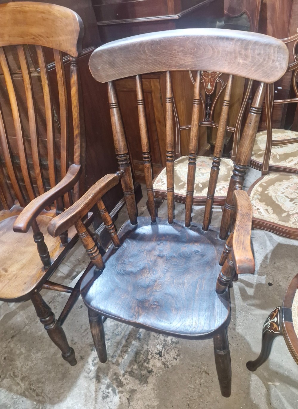 A set of four late Victorian wooden Windsor kitchen armchairs featuring spindle backs, shaped timber seats, turned legs, and stretchers. View III