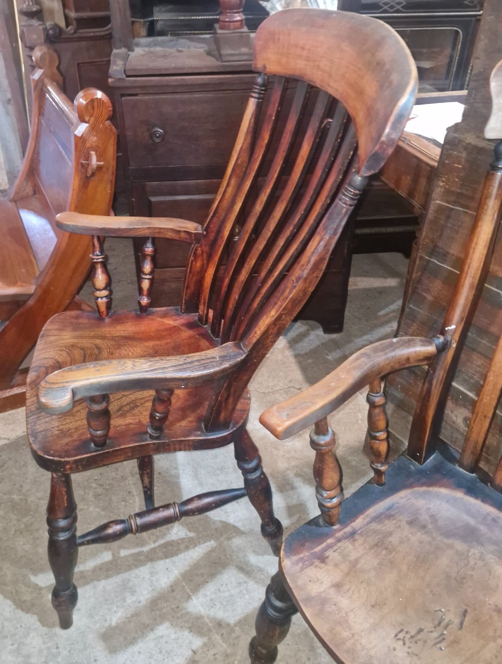 A set of four late Victorian wooden Windsor kitchen armchairs featuring spindle backs, shaped timber seats, turned legs, and stretchers. View V