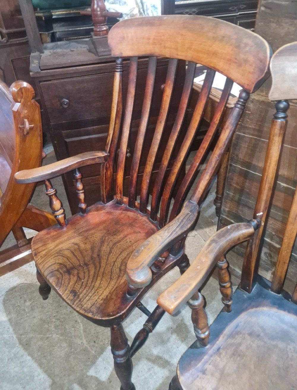 A set of four late Victorian wooden Windsor kitchen armchairs featuring spindle backs, shaped timber seats, turned legs, and stretchers. View VI