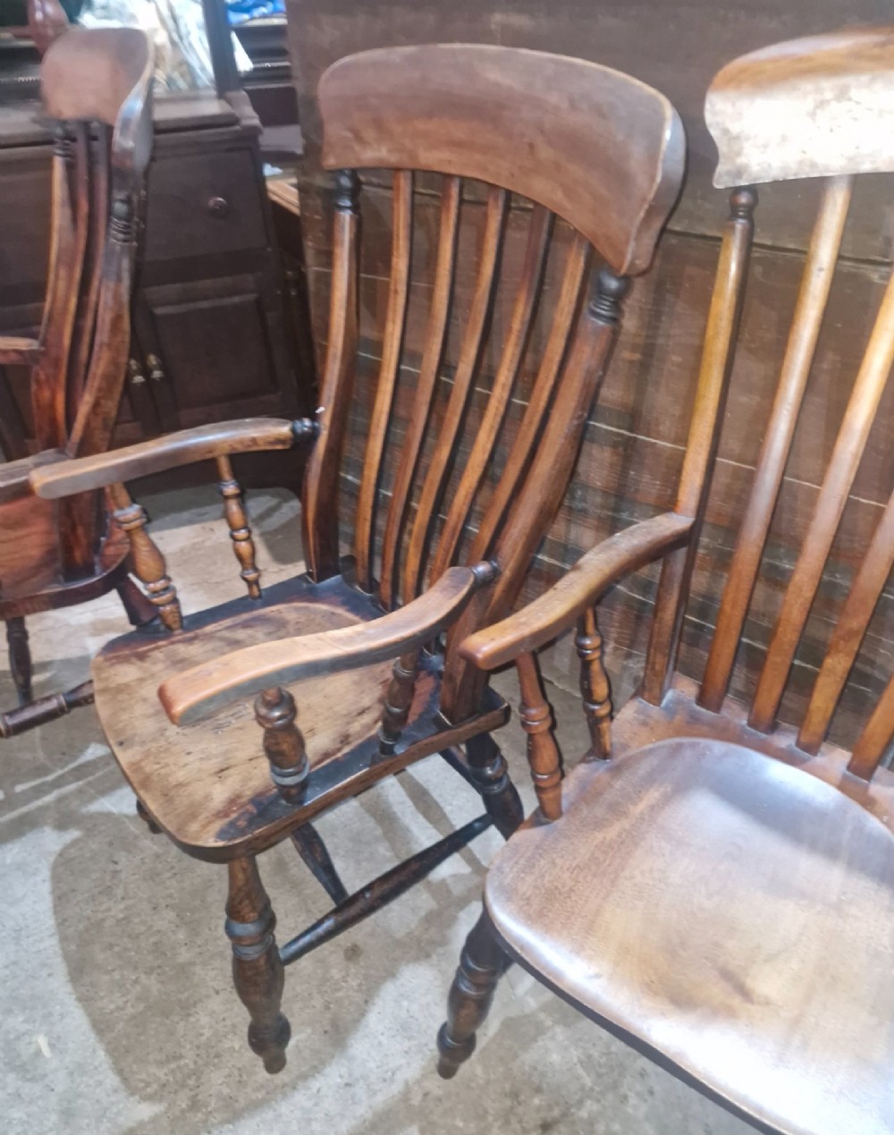 A set of four late Victorian wooden Windsor kitchen armchairs featuring spindle backs, shaped timber seats, turned legs, and stretchers. View VIII