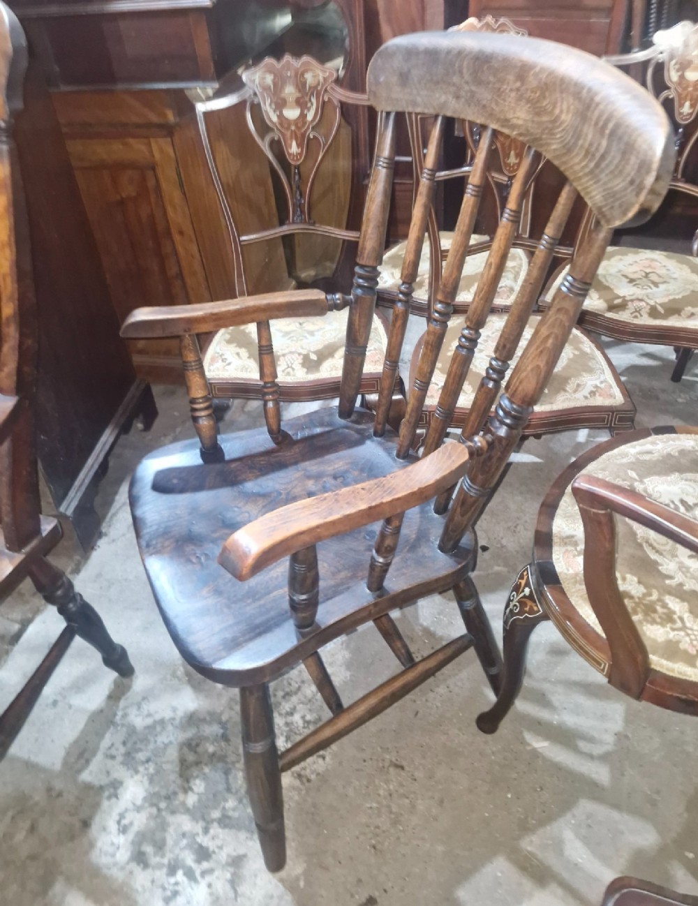 A set of four late Victorian wooden Windsor kitchen armchairs featuring spindle backs, shaped timber seats, turned legs, and stretchers. View X