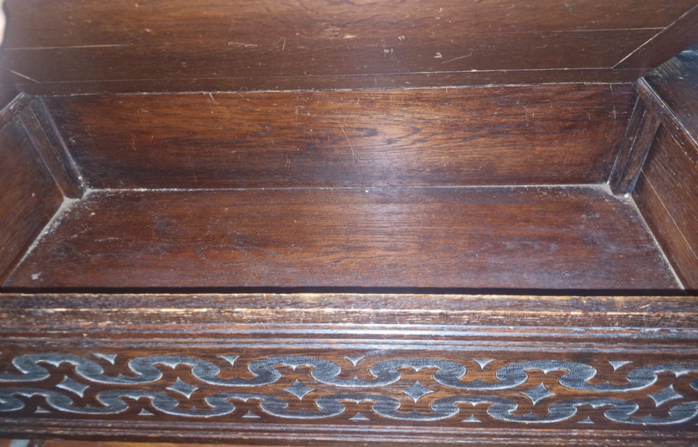 A dark oak monks bench featuring a carved diamond-patterned backrest, turned arm supports, carved front panel, and a lift-up seat. View IX