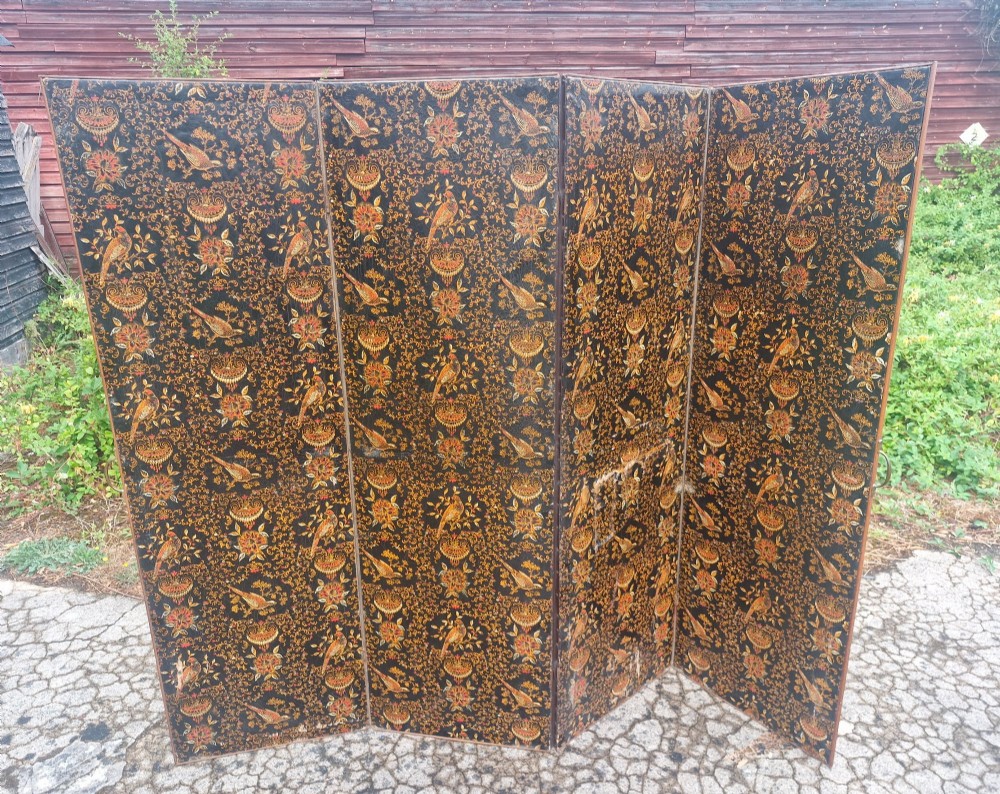 A late Victorian four-panel folding screen made of painted canvas featuring repeating golden bird and floral patterns on a dark black background.