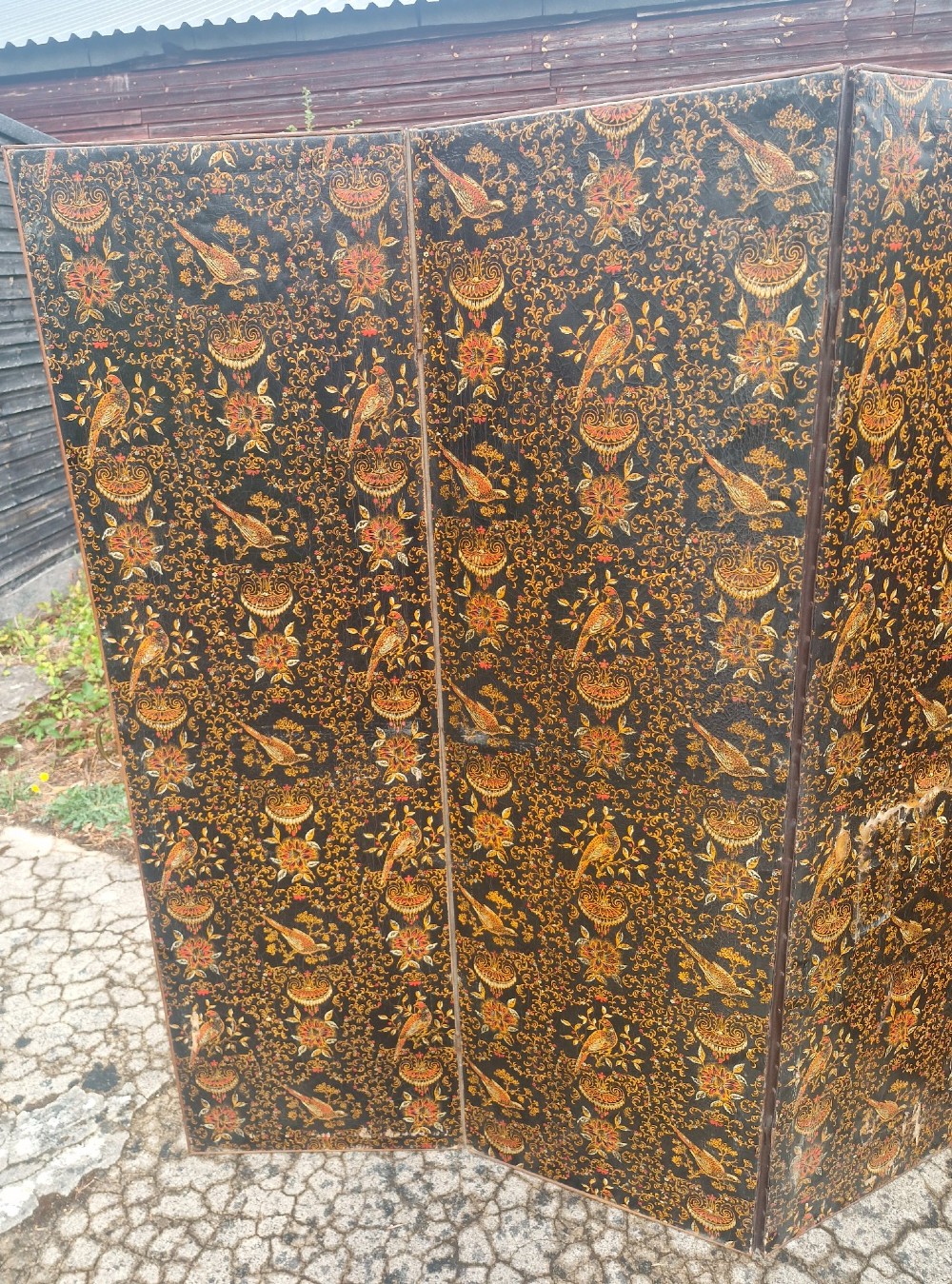 A late Victorian four-panel folding screen made of painted canvas featuring repeating golden bird and floral patterns on a dark black background. View IV