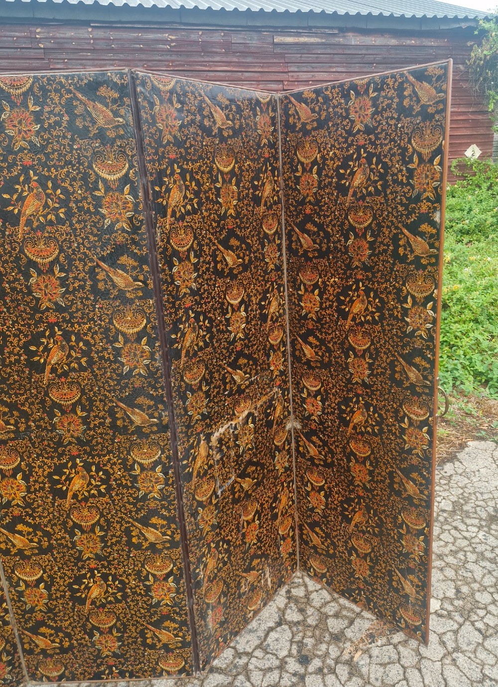 A late Victorian four-panel folding screen made of painted canvas featuring repeating golden bird and floral patterns on a dark black background. View V