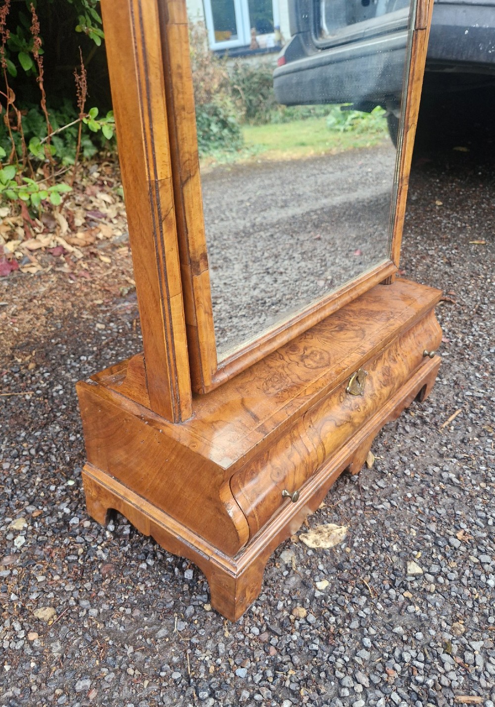 An 18th-century style walnut toilet mirror with a shaped frame supported on a box base containing a single drawer with brass hardware. View V
