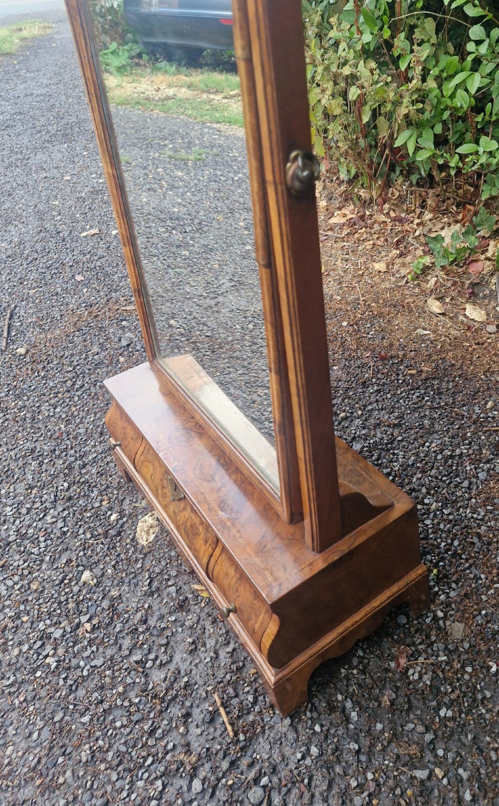 An 18th-century style walnut toilet mirror with a shaped frame supported on a box base containing a single drawer with brass hardware. View VII