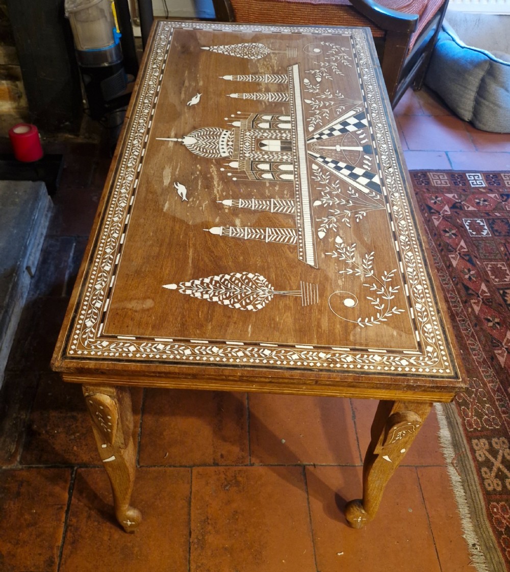 A rectangular warm brown hardwood table featuring detailed white bone inlay depicting the Taj Mahal surrounded by floral borders and curved inlaid legs. View V