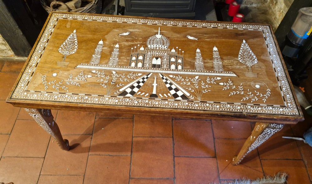 A rectangular warm brown hardwood table featuring detailed white bone inlay depicting the Taj Mahal surrounded by floral borders and curved inlaid legs. View VI