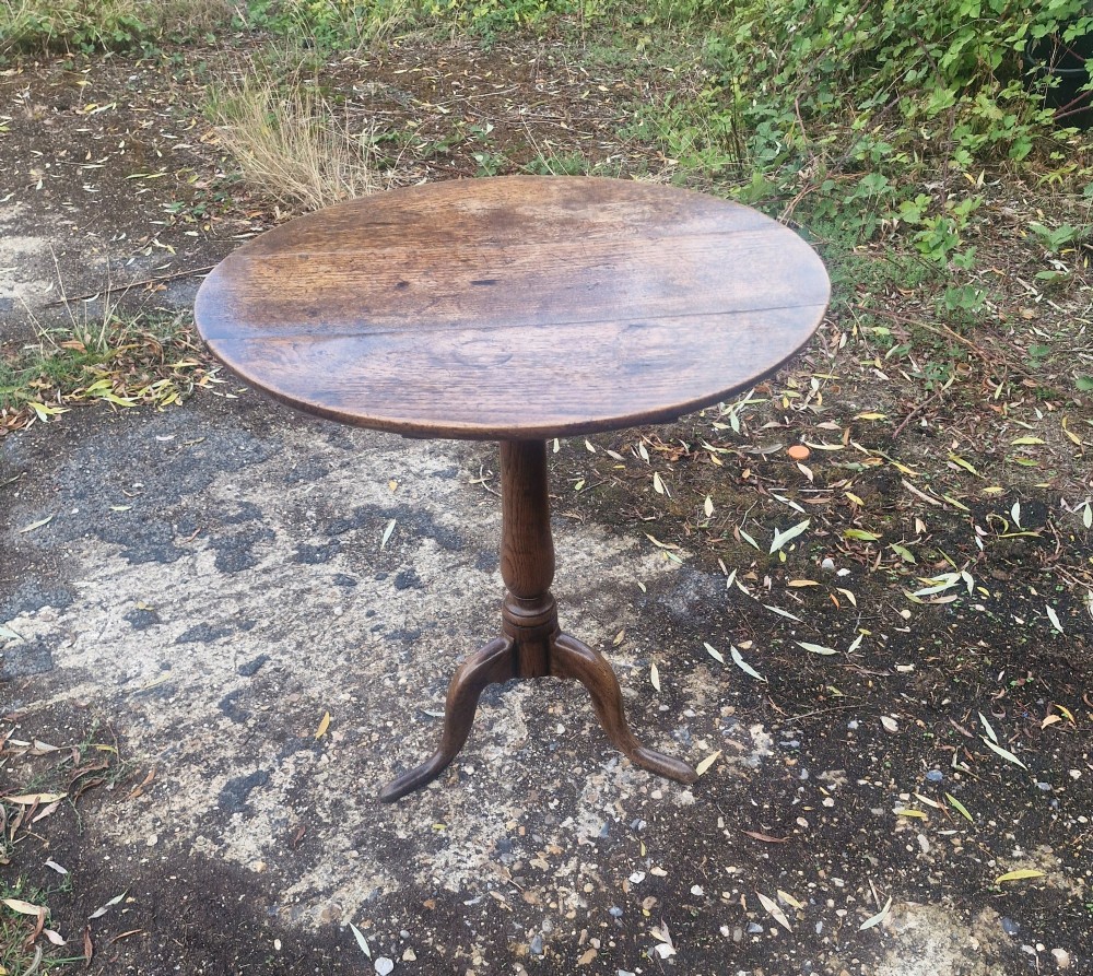 A late Georgian oak tripod table with a circular tilt-top surface positioned vertically, supported by a turned column and three cabriole legs. View III