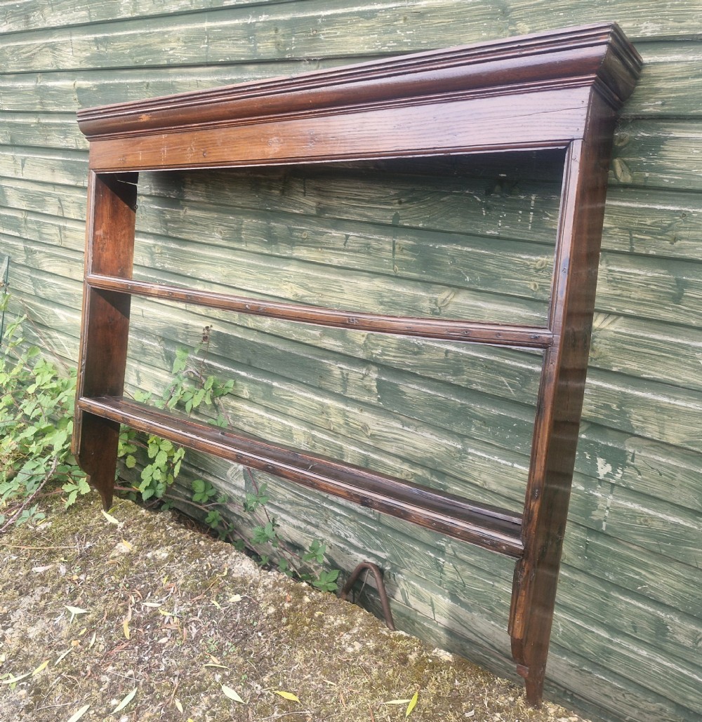 An antique dark oak wall-mounted plate rack featuring a moulded top cornice and two grooved display shelves. View III