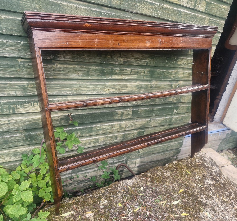 An antique dark oak wall-mounted plate rack featuring a moulded top cornice and two grooved display shelves. View VI