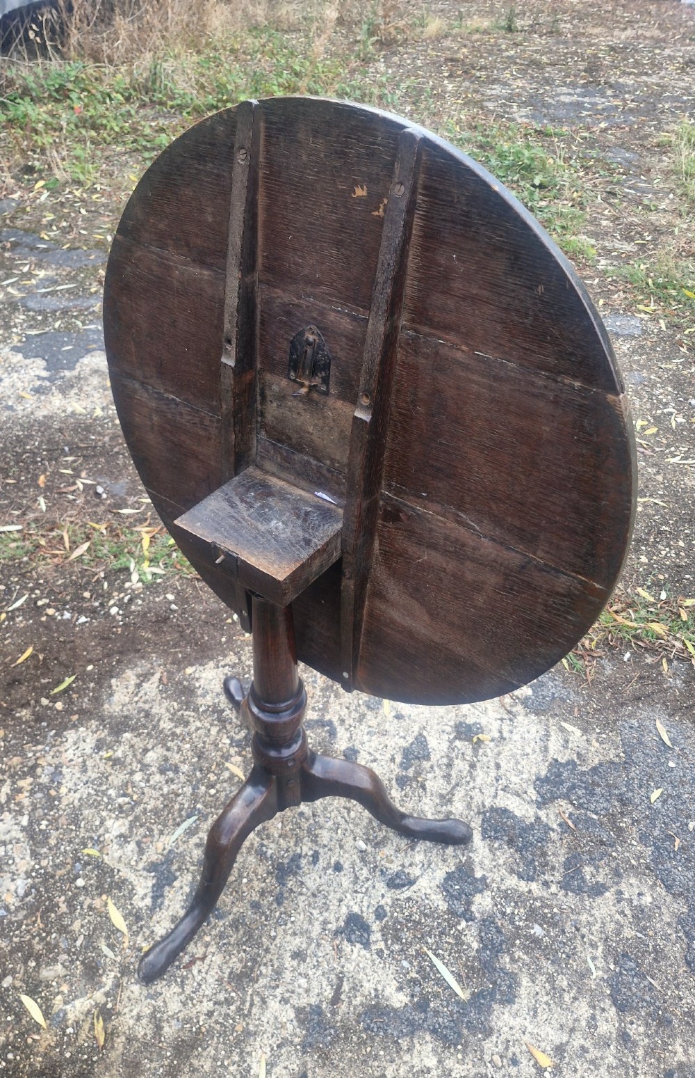 A dark oak 19th-century occasional table featuring a circular top tilted vertically on a turned pedestal with three cabriole legs. View II