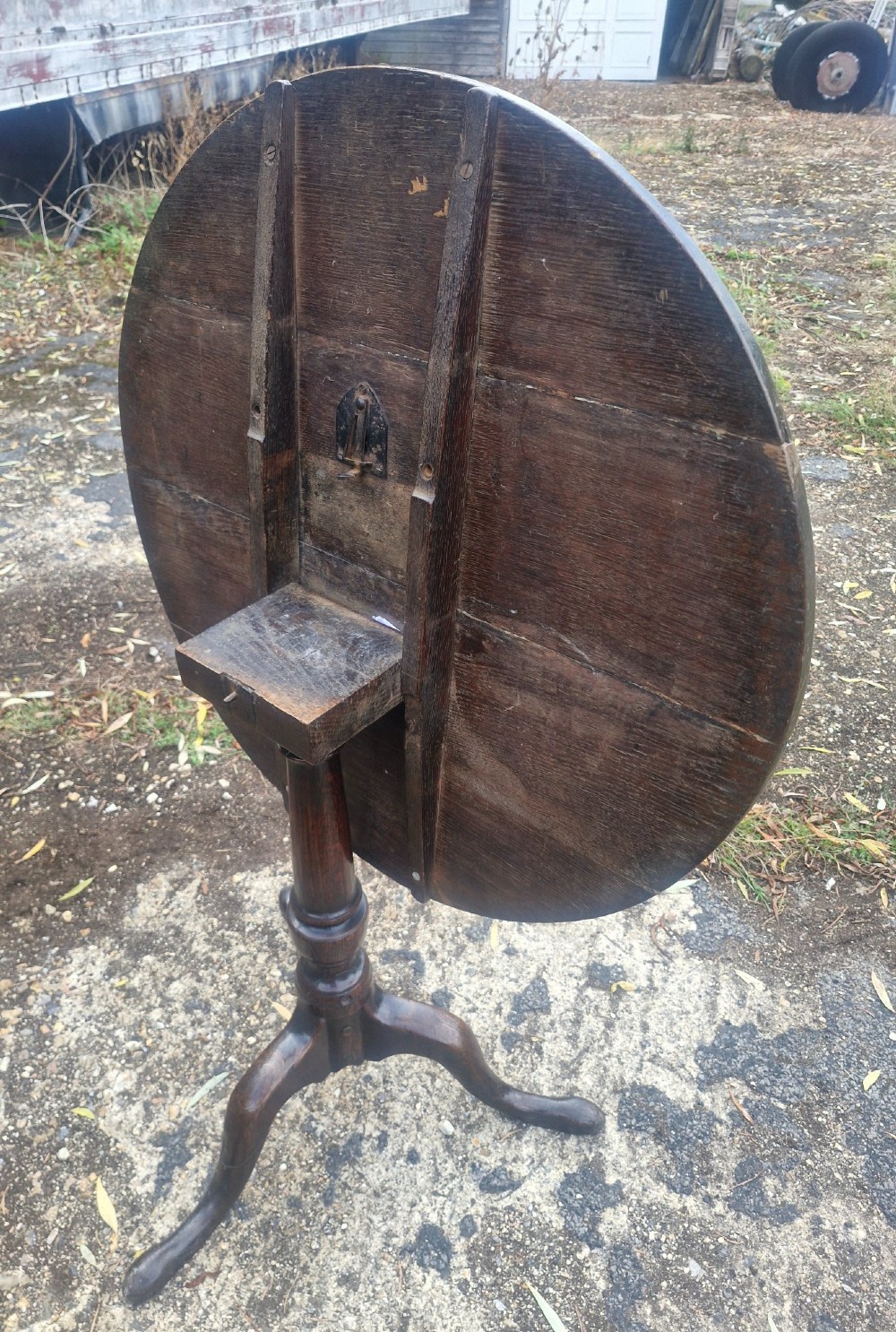 A dark oak 19th-century occasional table featuring a circular top tilted vertically on a turned pedestal with three cabriole legs. View IV