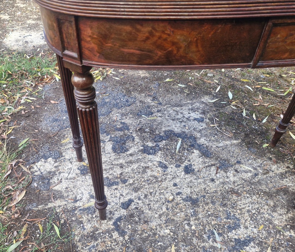 An early 19th-century mahogany demilune foldover tea table featuring a reeded apron and four reeded legs in the Gillows style. View V