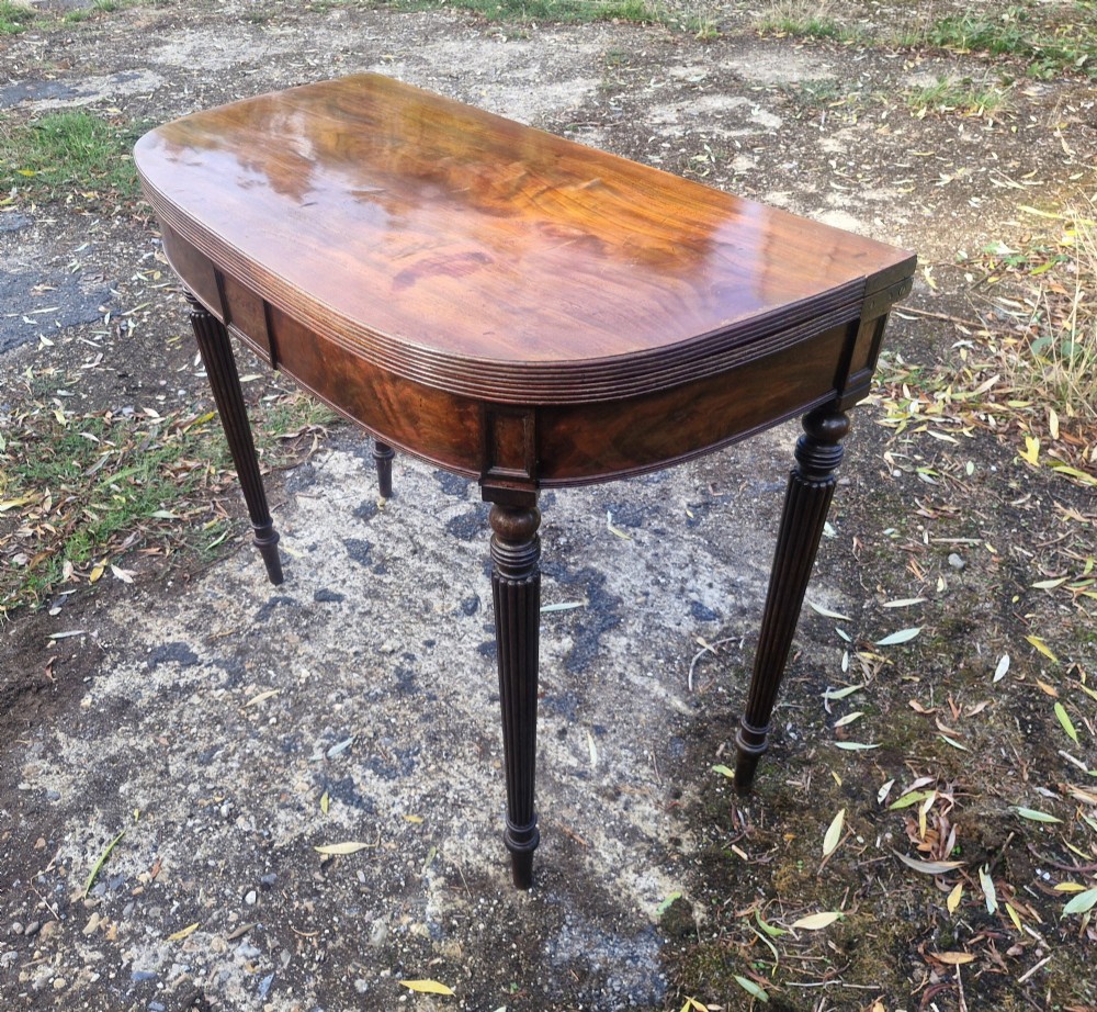 An early 19th-century mahogany demilune foldover tea table featuring a reeded apron and four reeded legs in the Gillows style. View VI