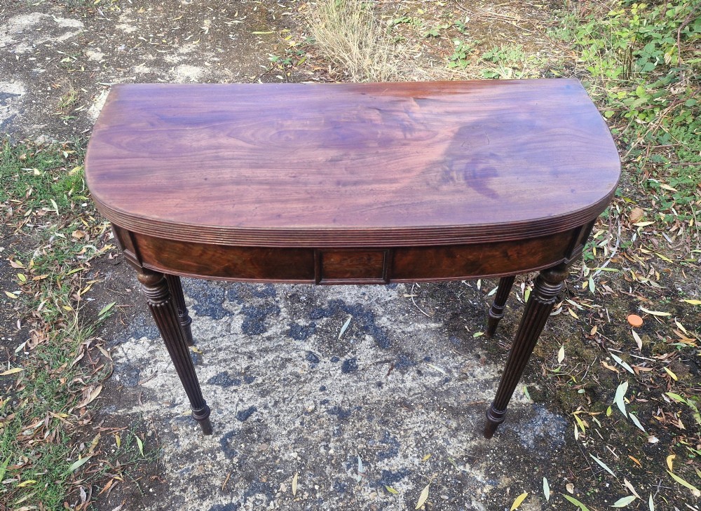 An early 19th-century mahogany demilune foldover tea table featuring a reeded apron and four reeded legs in the Gillows style. View X